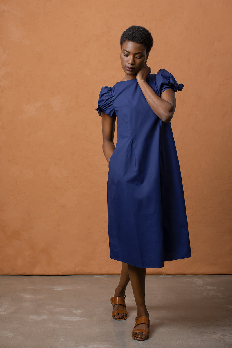 The puffy sleeve midi dress has side seam pockets and button fixtures that run along the center of the back.