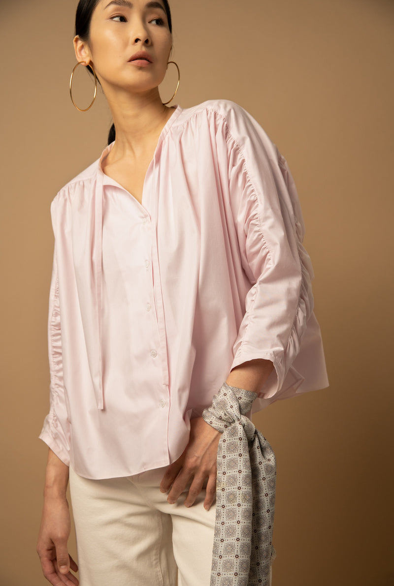 The poplin peasant top has natural shell buttons down the middle and two ribbons to tie into a bow at the collarbone. 